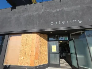 Restaurant storefront boarded with OSB and plywood after a vehicle crash