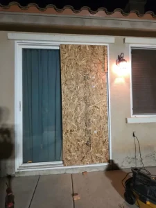 Broken sliding glass door secured with a full OSB panel during a late-night call